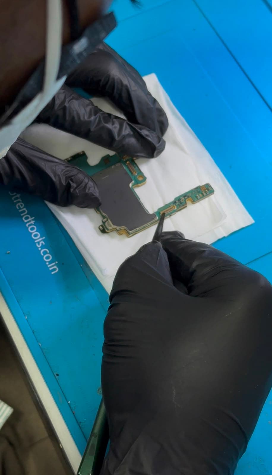 ICARE technician performing board-level logic board repair on a phone